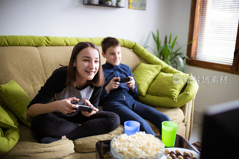 男孩和女孩坐在客厅里一起玩电子游戏