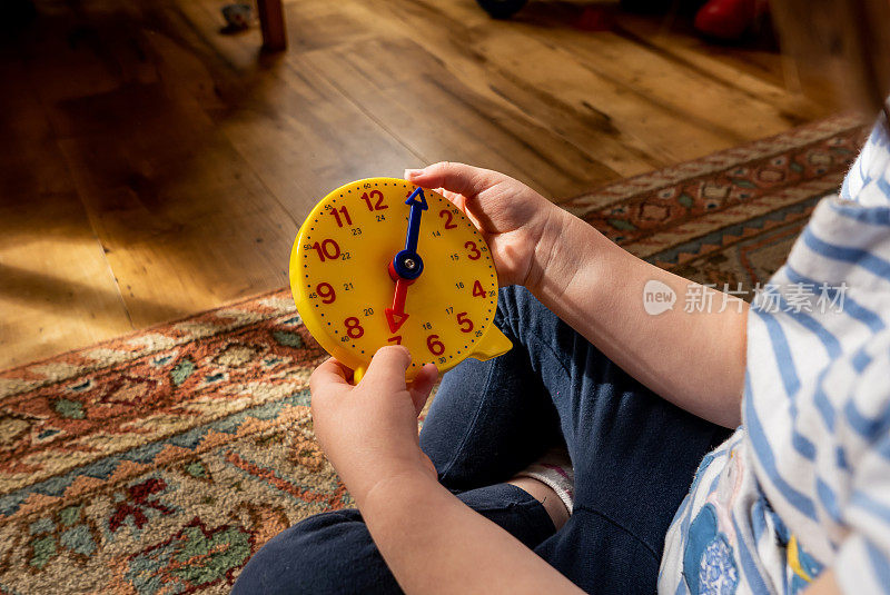 一个小女孩正在用一个24小时玩具钟学习报时