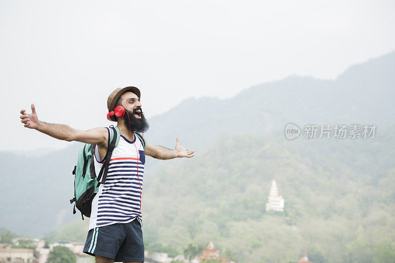 年轻的大胡子男子听音乐在山车站:-库存照片