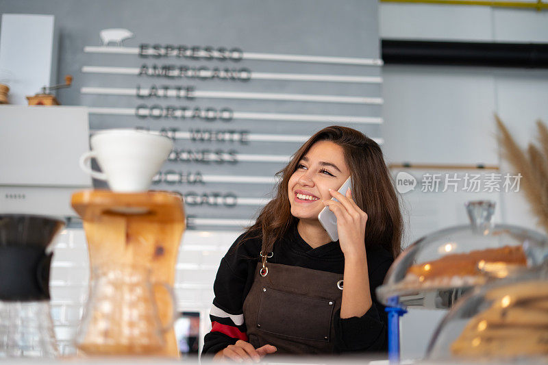 女咖啡师在咖啡店用智能手机点外卖