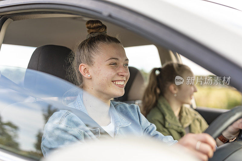 自豪的年轻女子开着自己的第一辆车载着朋友