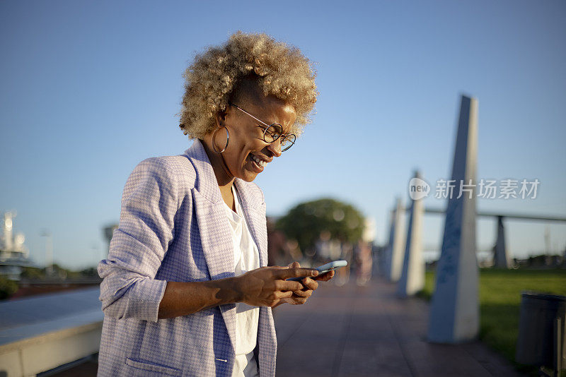 年轻的西班牙裔黑人女性在户外使用智能手机