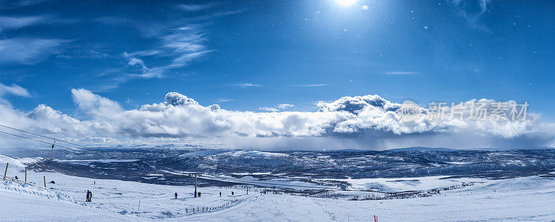 斯堪的那维亚山脉的景色非常美丽，人们在滑雪缆车上。晴朗的日子下着一点雪，很多雪，蓝色的天空飘着蓬松的云，小雪花在阳光下闪耀