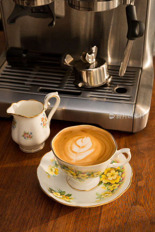 家庭咖啡师-自制的白色咖啡在古董骨瓷杯古董胡桃木桌子上