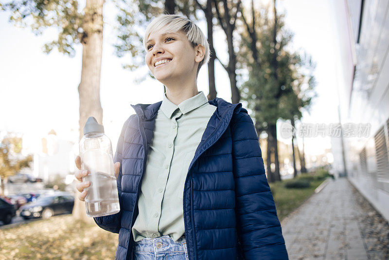 一个快乐的女孩在散步的肖像，提着一个水瓶