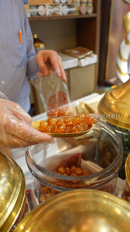 在Kadıköy历史集市上，小贩准备把一铲芝麻橙冰糖装到袋子里