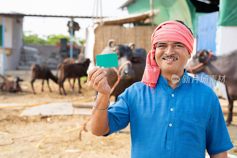 微笑的印度奶农展示绿卡，通过看着镜头-概念广告，促销和成功