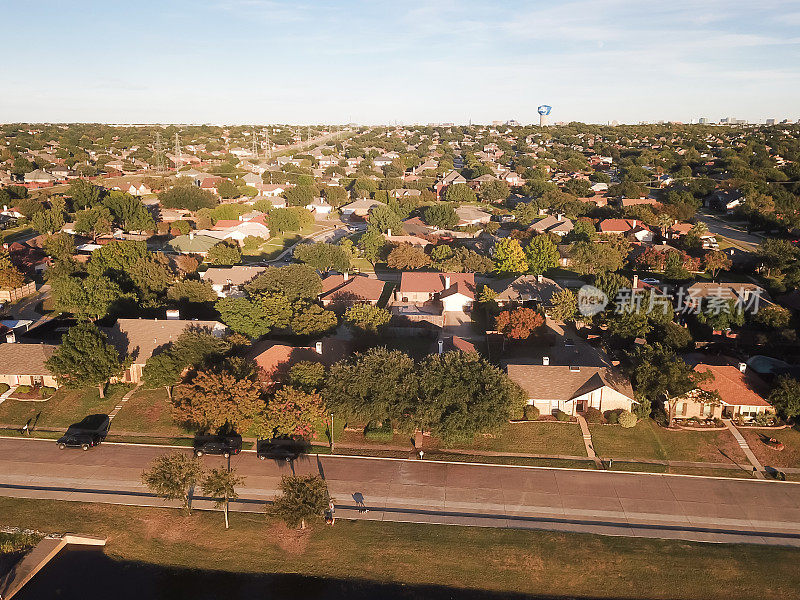 鸟瞰线传输塔电力塔旁边的居民区与达拉斯市中心天际线背景附近卡罗顿，得克萨斯州，美国