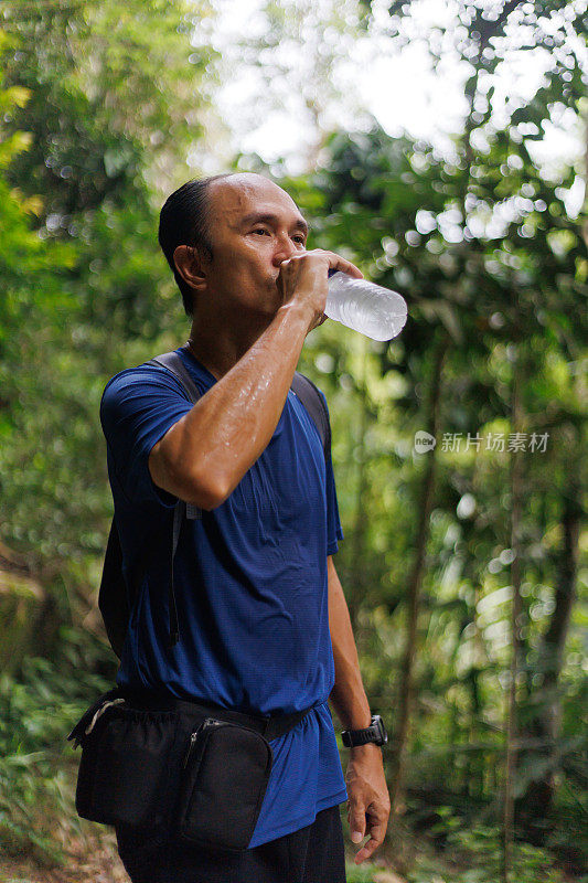 年老男子徒步旅行，休息时补充水分