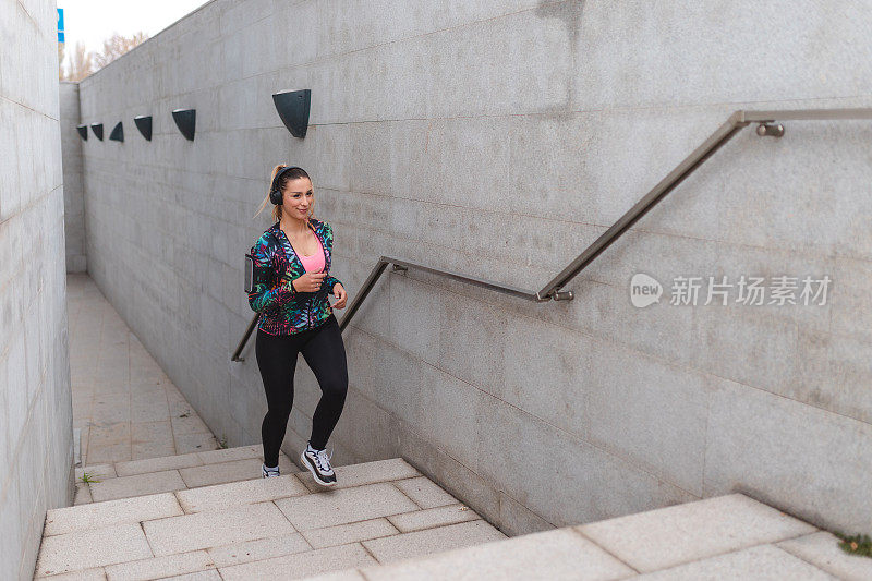 健身年轻女运动员在城市环境中跑步上楼梯