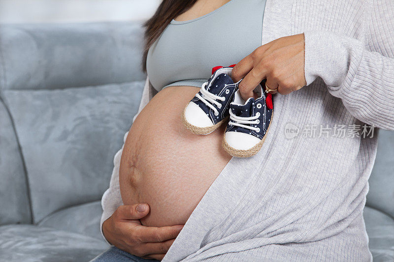孕妇腹部为未出生婴儿准备的小鞋子