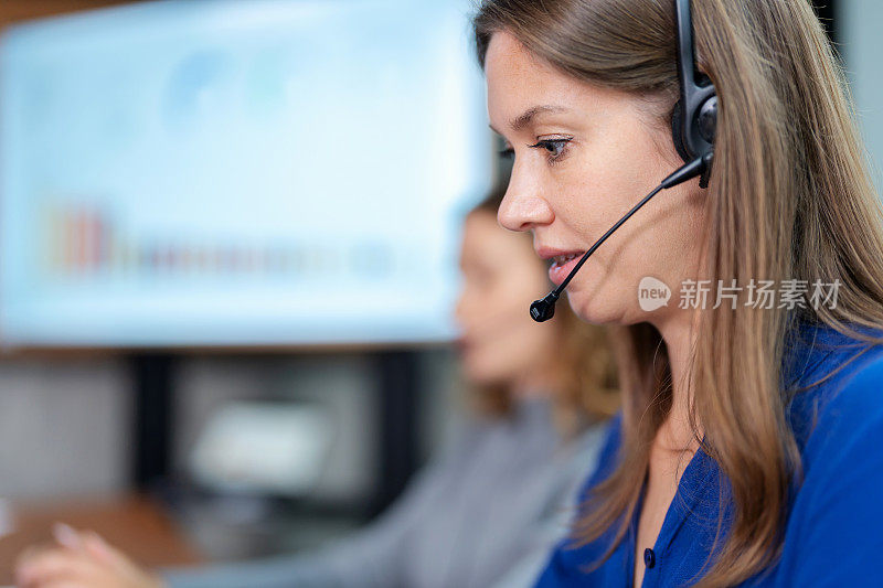 呼叫中心接线员接听电话，协助客户使用服务。呼叫中心女士戴着耳机和麦克风在办公室与客户交谈并回答问题的特写。