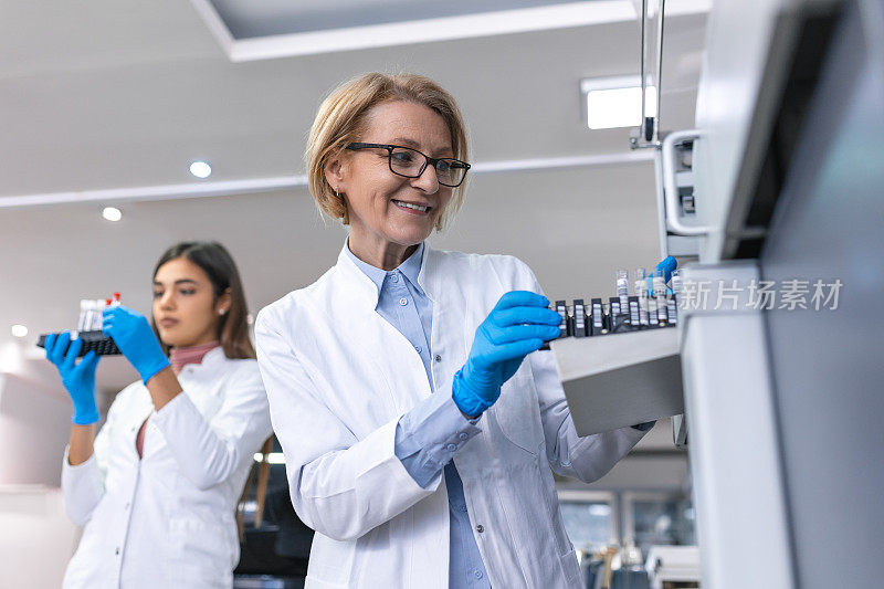 在实验室里，女科学家检查医疗设备，用血液样本分析试管。药物实验室研究人员团队工作。