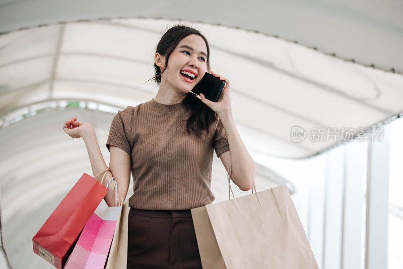 一个女购物者拿着购物袋打电话