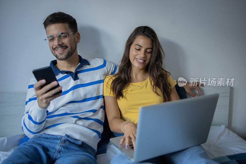 年轻夫妇在家里使用智能手机和笔记本电脑