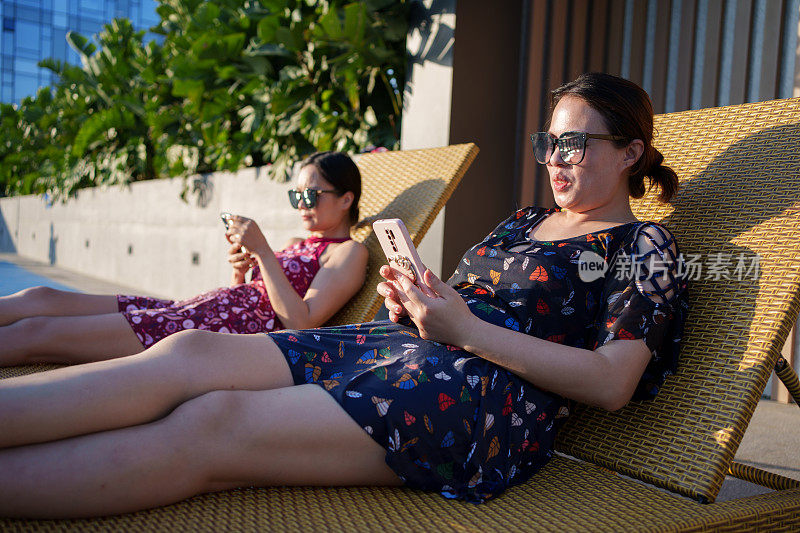 女人在沙滩椅上玩智能手机
