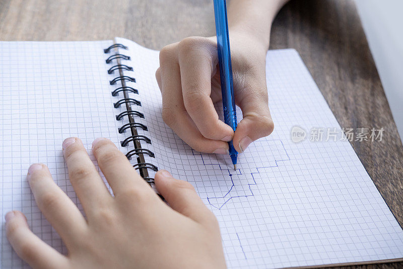 孩子，10岁的男孩在格子笔记本上画图形听写，左边一行，下面两格，家庭学校准备，远程学习，创造性的教育方法