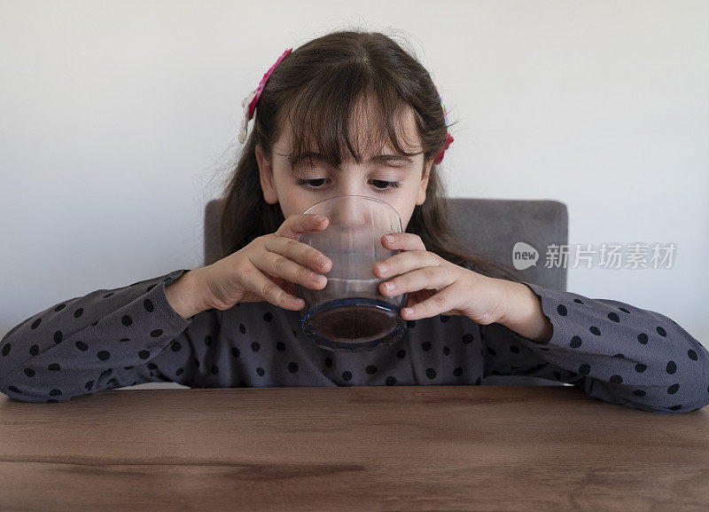 小女孩正在喝一杯巧克力牛奶