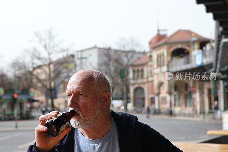 一个胡子花白的男人在喝啤酒