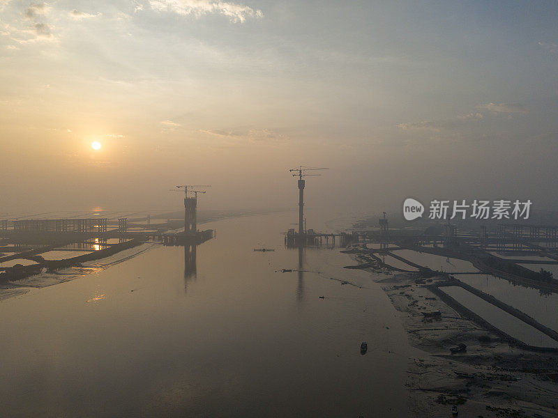 日出时正在施工的跨海大桥建筑工地的航空照片