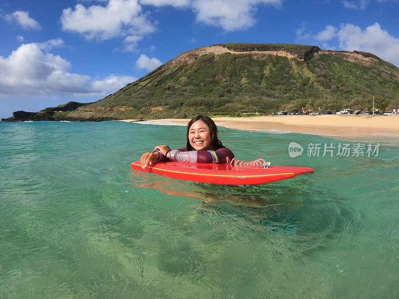 一个快乐的年轻日本女人在夏威夷玩滑板