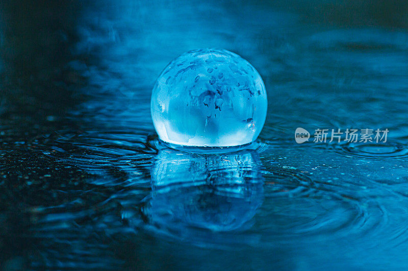 洪水。地球背景下的水。玻璃透明球。自然灾害。暴雨。水坑里的雨滴。