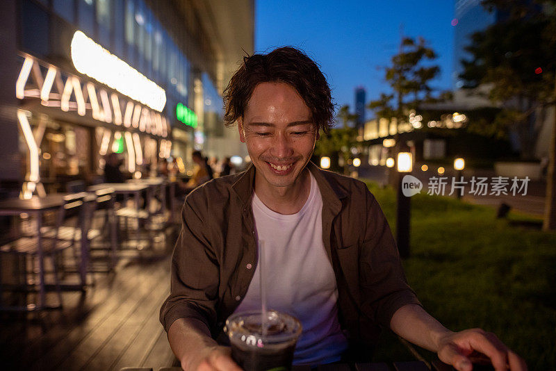 日本男子晚上在户外咖啡馆放松