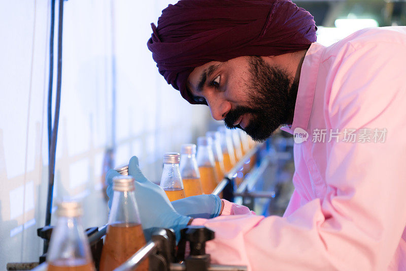 果汁生产线的产品质量控制人员进行产品质量检查，确保生产的产品质量良好
