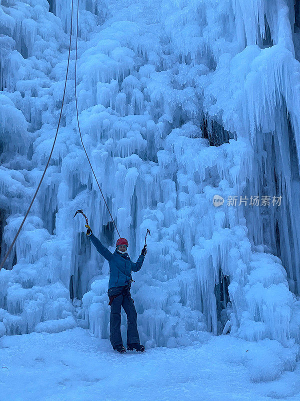 竖直方向:一名欢快的白人女子在攀冰时张开双臂。