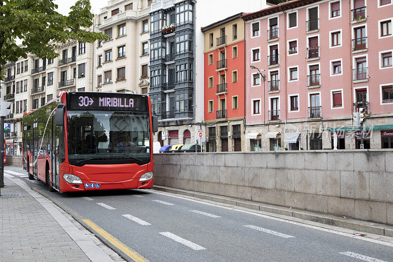 西班牙，红色公共汽车停在五颜六色的公寓楼林立的城市街道上