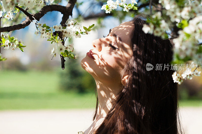 美丽的年轻女子闻着花香