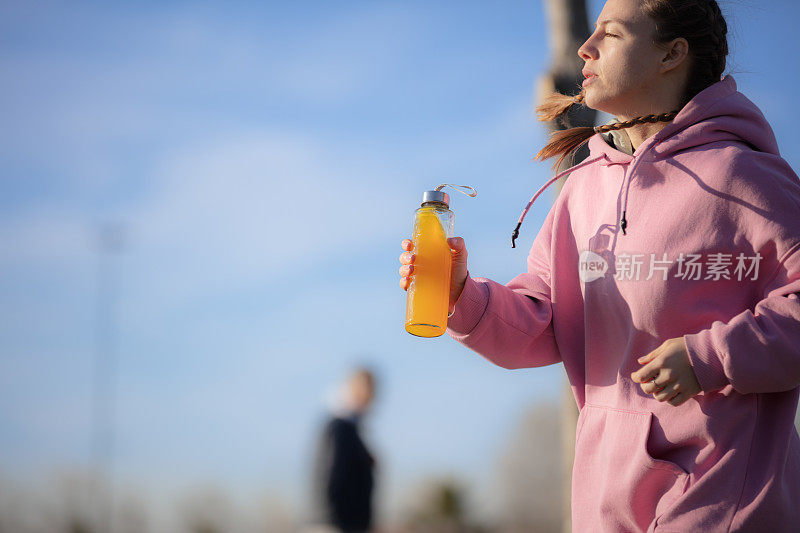 年轻女子在公园慢跑时补水。