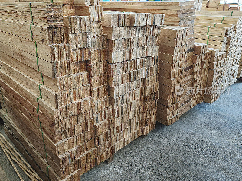 在家具厂储存松木原木。锯木厂里成堆的木板。出售锯木板的仓库，在建筑物内。木材堆砌是建筑材料行业的坯料