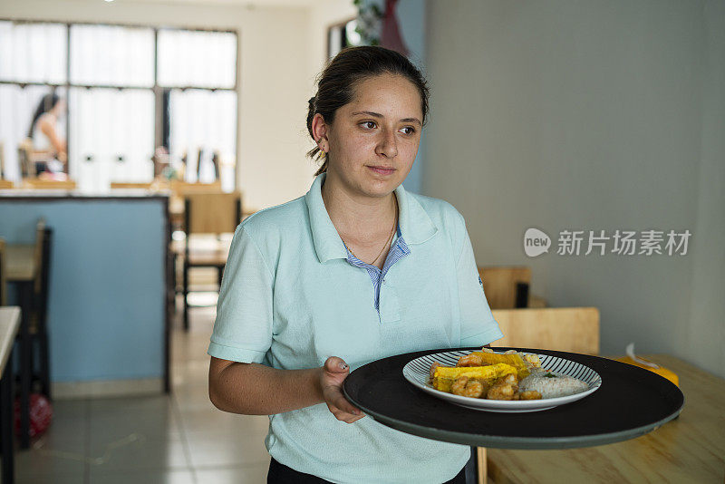 一位拉丁海鲜妇女正忙着他的生意，自豪地向镜头展示他的一杯虾鸡尾酒，他将把它带到桌子上给他的顾客