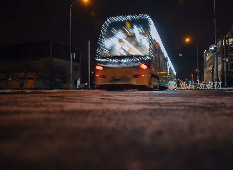 灯火通明的公共汽车在夜晚的城市街道上快速行驶