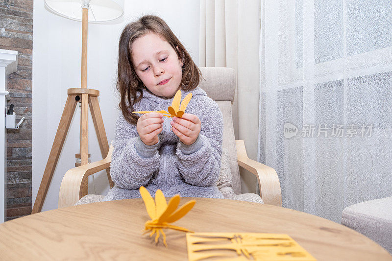 一个女孩，一个7岁的白人孩子，从一个木制建筑工人那里收集一只蜻蜓。激发创造力。