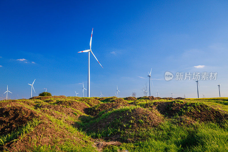 在蓝天下的绿色农田上，风力涡轮机在运转