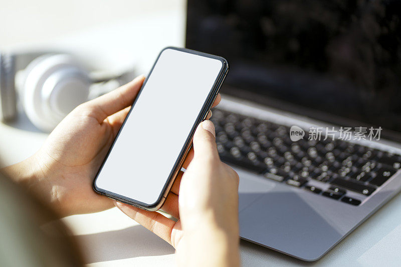 裁剪后的女子手持空白屏幕的智能手机，在社交网站上发信息。模型