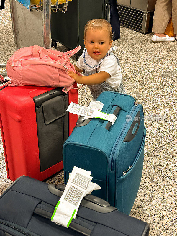 在葡萄牙机场办理登机手续的地方，一个婴儿在行李箱旁