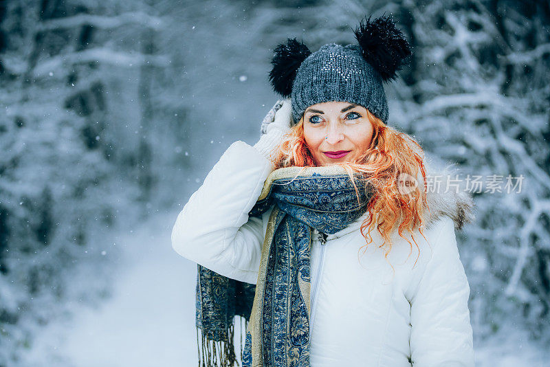 幸福的女人在冬天森林附近的白雪皑皑的草地