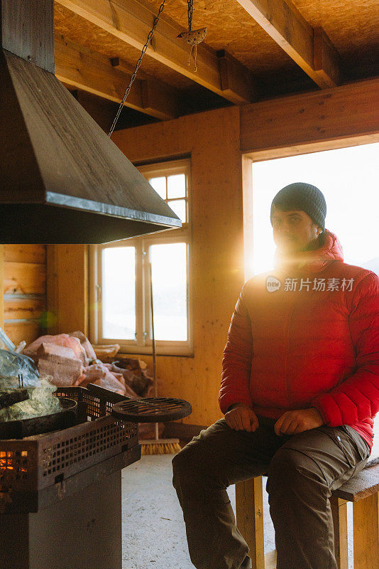 挪威峡湾，一名男子在炉火旁取暖