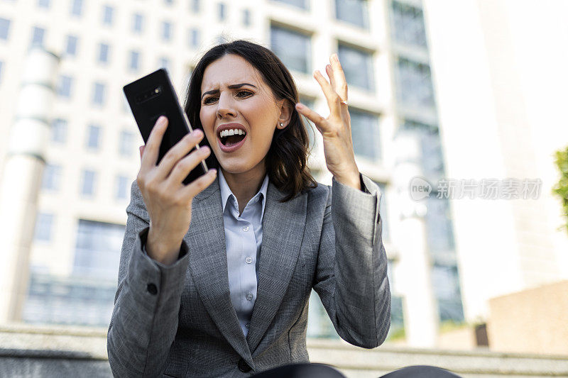 女商人在办公楼前尖叫着用手机