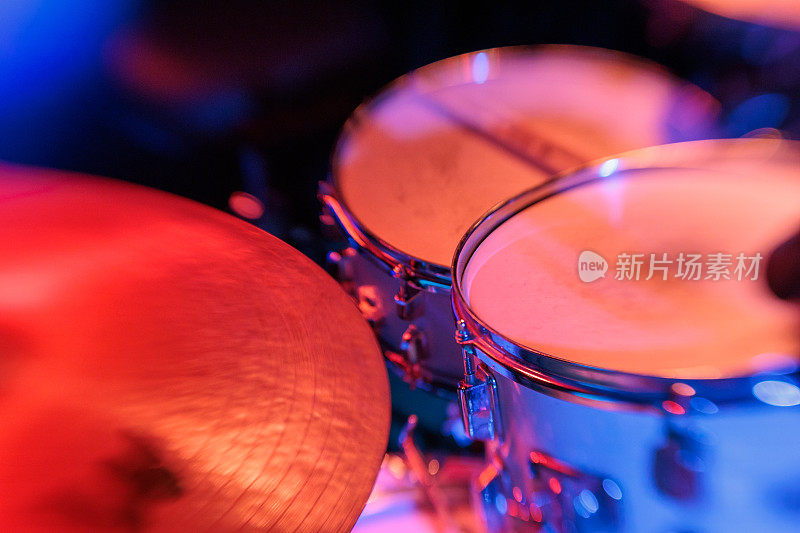 舞台上鼓套件的特写与充满活力的红色灯光-现场音乐表演设备