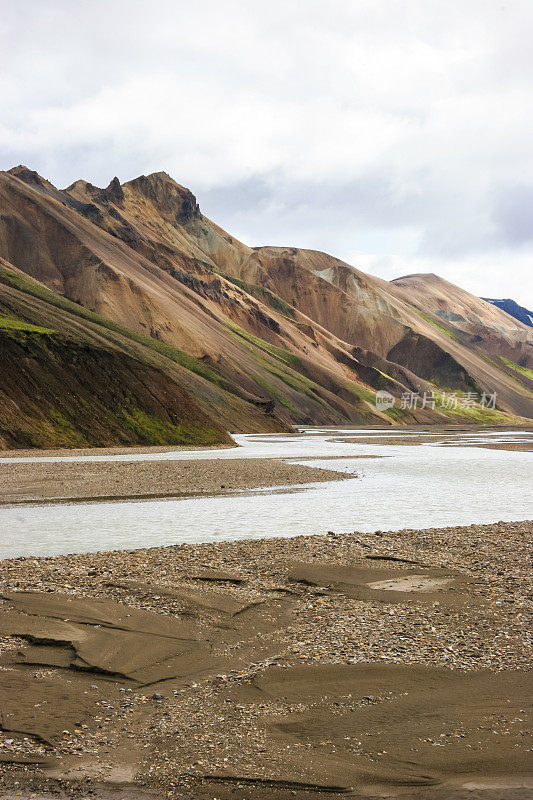 冰岛Laugevegur步道起点的Landmannalaugar周围引人注目的山景，显示了洪水平原上的冰川径流河