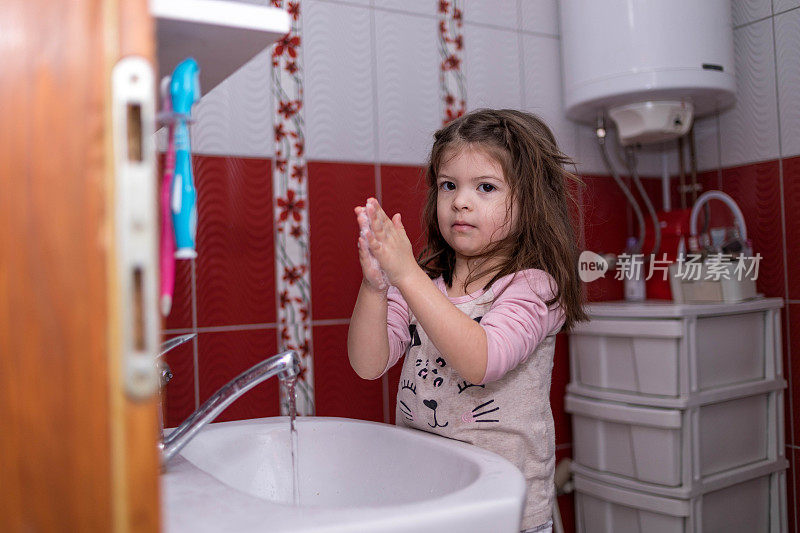 可爱的小女孩在浴室洗手。