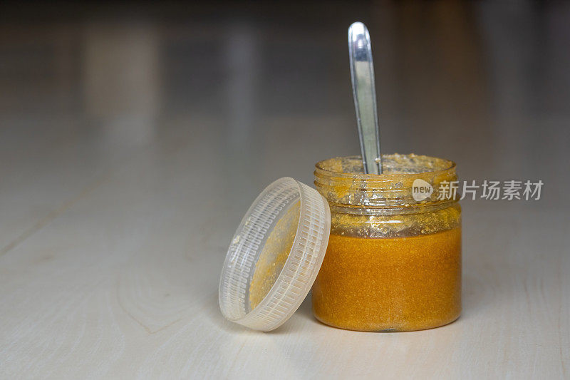 一罐酥油或澄清黄油，用钢勺放在木质纹理的背景上。酥油富含重要的营养物质，如维生素A、omega-3脂肪酸和共轭亚油酸。