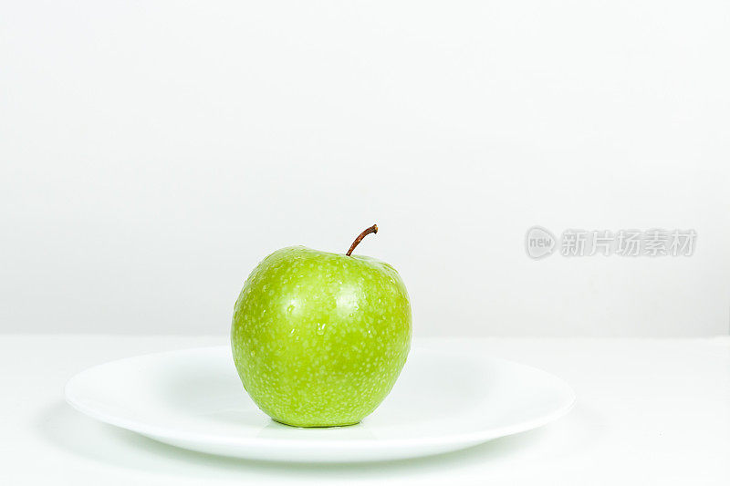 在盘子里有水滴的青苹果