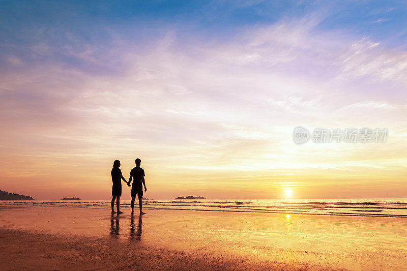 一对情侣一起站在沙滩上思考生活