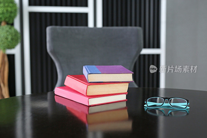 戴眼镜的木桌上放着精装书。教育背景。