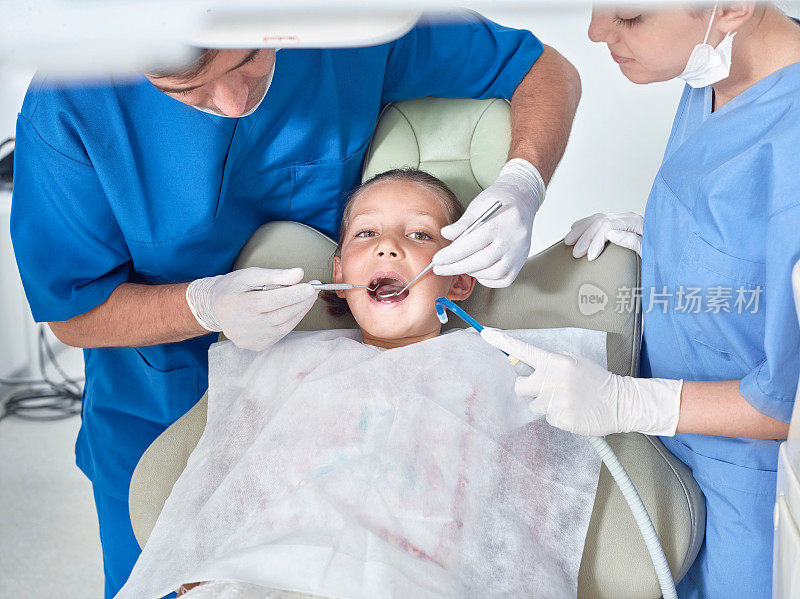 牙医兼助理检查小女孩的牙齿